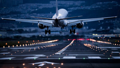 Aircraft Lands on Illuminated Runway Amidst City Lights /aviation , airport , landing , transportation , infrastructure