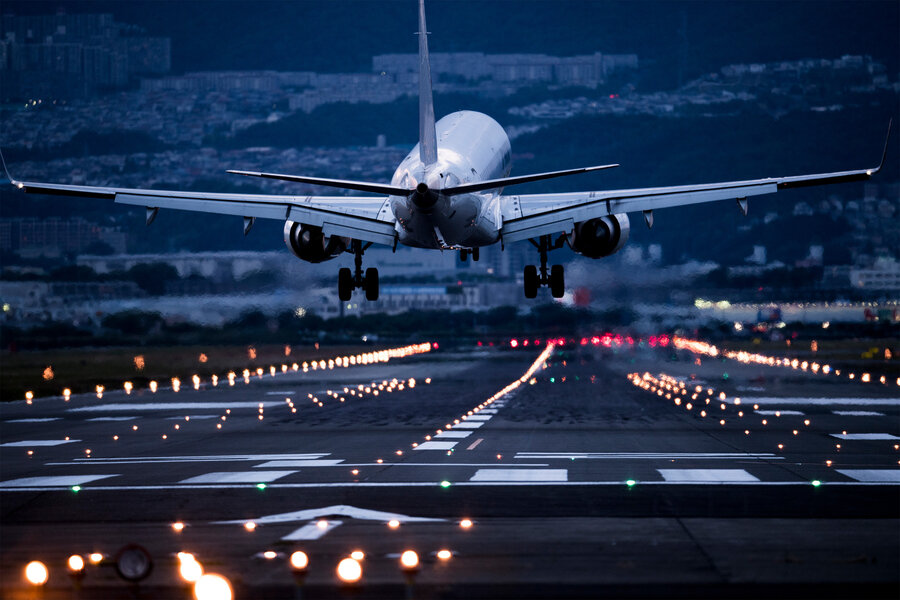 Aircraft Lands on Illuminated Runway Amidst City Lights /aviation , airport , landing , transportation , infrastructure